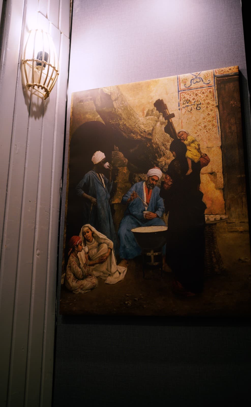 Orientalist canvas lit by wall sconce